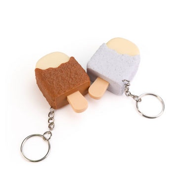 Two small novelty keychains shaped like ice cream popsicles, one brown and one light gray, shown on a plain white background.