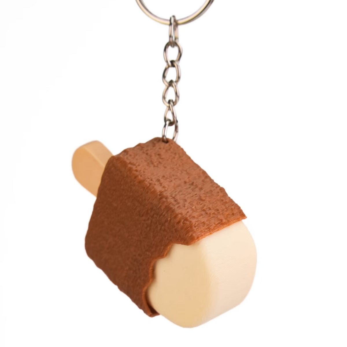 A novelty keychain shaped like a chocolate-covered ice cream stick, featuring a brown frosting-like top and a pale cream-colored bottom, attached to a silver metal chain on a white background.