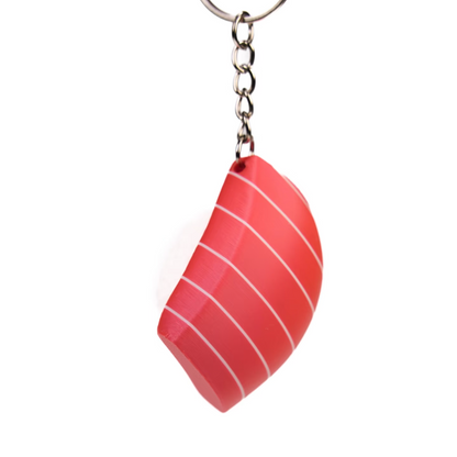 A novelty keychain shaped like a slice of red salmon sushi with white stripes, attached to a silver metal split ring, shown on a plain white background.