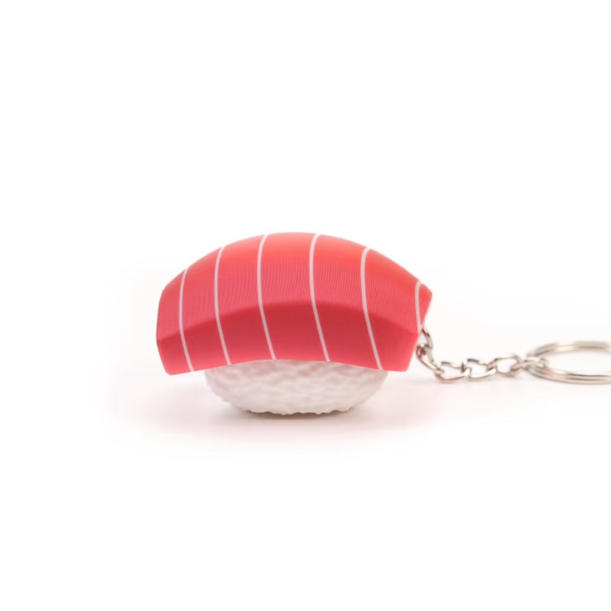 A small sushi-shaped keychain charm with a pink top and white base, attached to a silver metal key ring, shown on a plain white background.
